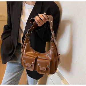 Detail of brown faux leather shoulder bag with silver rivets and double front pockets