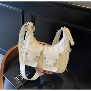 Detail of off-white crescent shoulder bag with metal eyelet strap and dual front pockets