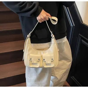 Detail of cream-colored glossy leather shoulder bag with decorative dual pocket design