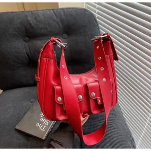 Close-up of red leather underarm bag with silver grommets and functional dual pockets