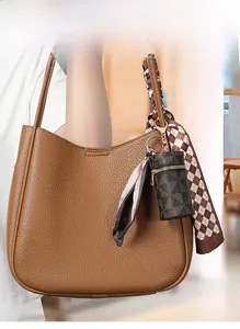 Dettaglio di un mini portamonete cilindrico con motivi geometrici su borsa marrone