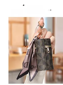 Dettaglio mini portamonete con motivo monogramma, hardware dorato e foulard in seta viola