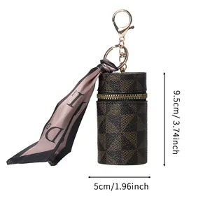 Mini portamonete cilindrico marrone con motivo geometrico, zip dorata e dettaglio foulard