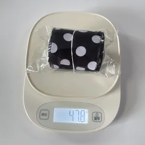 Detail view of black ribbon with white polka dots on a digital scale weighing 47.8g