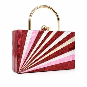 Detail of acrylic evening bag with red and pink marble stripes and gold ring handle