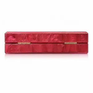 Detail view of gold metal hinges on acrylic clutch bag with red marble texture