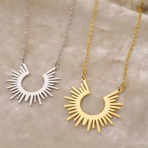 Minimalist 18K gold and silver sunburst pendant necklaces on beige velvet background