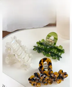 Close-up of acetate flower hair claws with rhinestone centers and gold metal spring