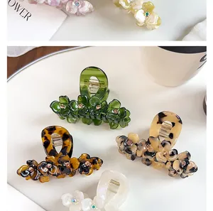 Detailed view of acetate flower hair claws with rhinestones in various elegant textures