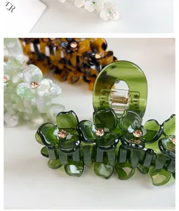 Close-up of green acetate hair claw with delicate 3D flowers and sparkling rhinestones