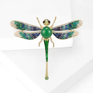 Élégante broche libellule aux ailes en émail vert et strass sur une base dorée