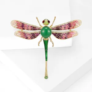 Détail macro de broche libellule avec ailes en émail dégradé et incrustation verte