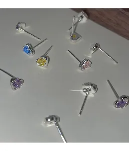 Macro shot of colorful heart-shaped zircon earrings with silver posts and engravings