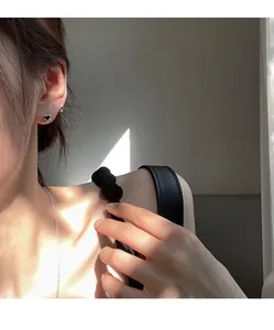 Close-up of black heart studs and delicate silver chain on model with natural lighting