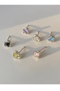 Macro detail of heart-shaped silver earrings with colorful zircon stones in six shades