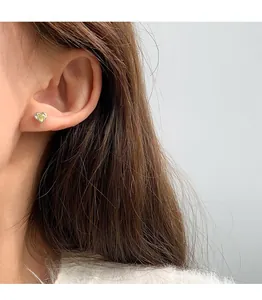 Close-up of heart-shaped silver stud earring with yellow gemstone worn by a model