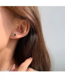 Close-up of heart-shaped earring with black zircon and silver frame on female ear