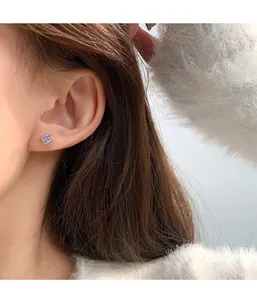 Close-up of heart-shaped earring with purple zircon stone on a model ear
