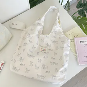 Close-up of cream canvas tote bag with blue cat pattern and rainbow logo label