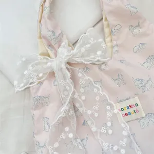Close-up of pink checkered tote bag featuring blue cat print and large lace bow detail