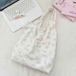 Detailed close-up of blue cat print canvas tote bag with large white lace bow