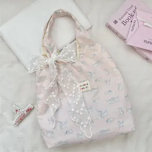 Close-up of pink checkered tote bag with white lace bow and cute cat print detail