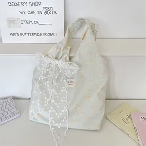 Detail of green canvas tote bag featuring a yellow cat print and large white lace bow