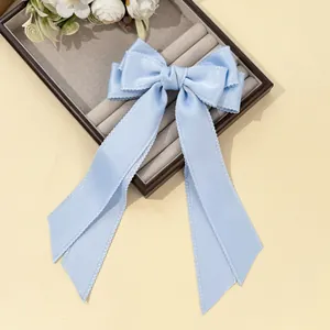 Close-up of light blue satin ribbon hair clip with delicate white lace edging detail