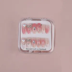 Detail of almond press-on nails with pink gradient and 3D silver bow and pearl heart