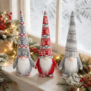Detail of three Christmas gnomes with knitted snowflake hats on a snowy windowsill