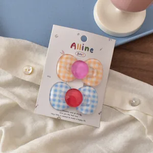 Detail of orange and blue checkered bow hair clips on a white fabric background
