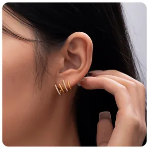Detailed view of gold C-shaped ear studs with multi-layer wrap and zircon stones