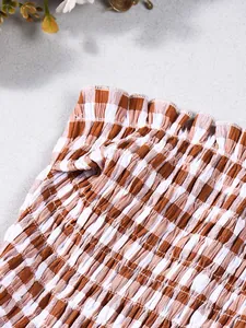 Nahaufnahme der elastischen Smok-Details und des braunen Gingham-Musters auf Baumwolle