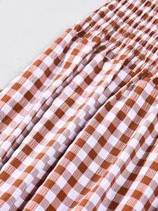 Detailaufnahme von braunem und weißem Gingham-Stoff mit feiner Smok-Arbeit