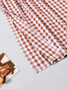 Detailaufnahme von braun-weißem Karostoff mit präziser Overlock-Naht am Saum