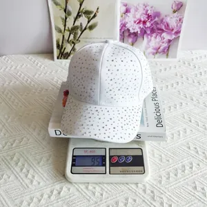 Detailed top view of white baseball cap with colorful rhinestones on a digital scale