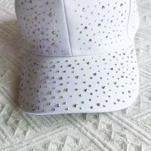 Close-up of white baseball cap with colorful rhinestones on a white textured fabric