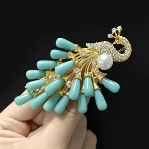Detailed close-up of peacock brooch with green water-drop beads and white pearls