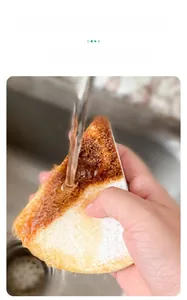 Action shot of water rinsing grease off heart-shaped wood pulp kitchen sponge