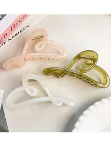 Close-up of heart-shaped hair claws in pink, olive green, and cream white on a ceramic plate