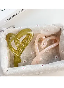 Detail of two translucent heart hair claws in olive green and light pink resin