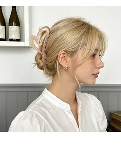 Detail of pink heart-shaped acrylic hair claw clip worn on a low bun hairstyle
