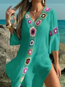 Detail van kleurrijke gehaakte bloemen en zijsplit op een blauwgroene boho strandjurk