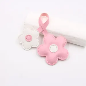 Detail of pink and white leather cherry blossom charms with white stitching on strap