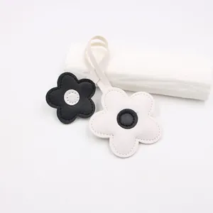 Detail of leather cherry blossom charms with fine stitching and black and white contrast