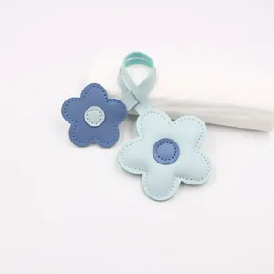 Close-up of blue leather flower charms with contrasting centers and visible white stitching