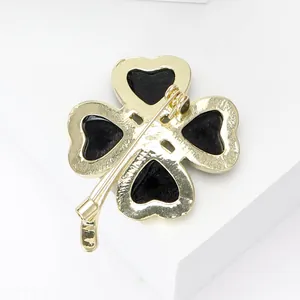 Elegante spilla a quadrifoglio dorata con intarsio cuore nero su pietra bianca