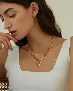 Detail of 14K gold plated Cuban chain necklace with a large geometric cone pendant on a model