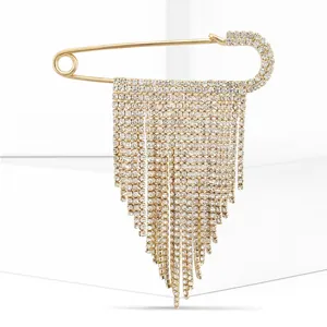 Detail of gold safety pin brooch with sparkling rhinestone tassels on white background