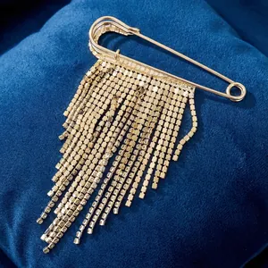 Elegant gold safety pin brooch featuring long multi-row rhinestone tassels on blue velvet